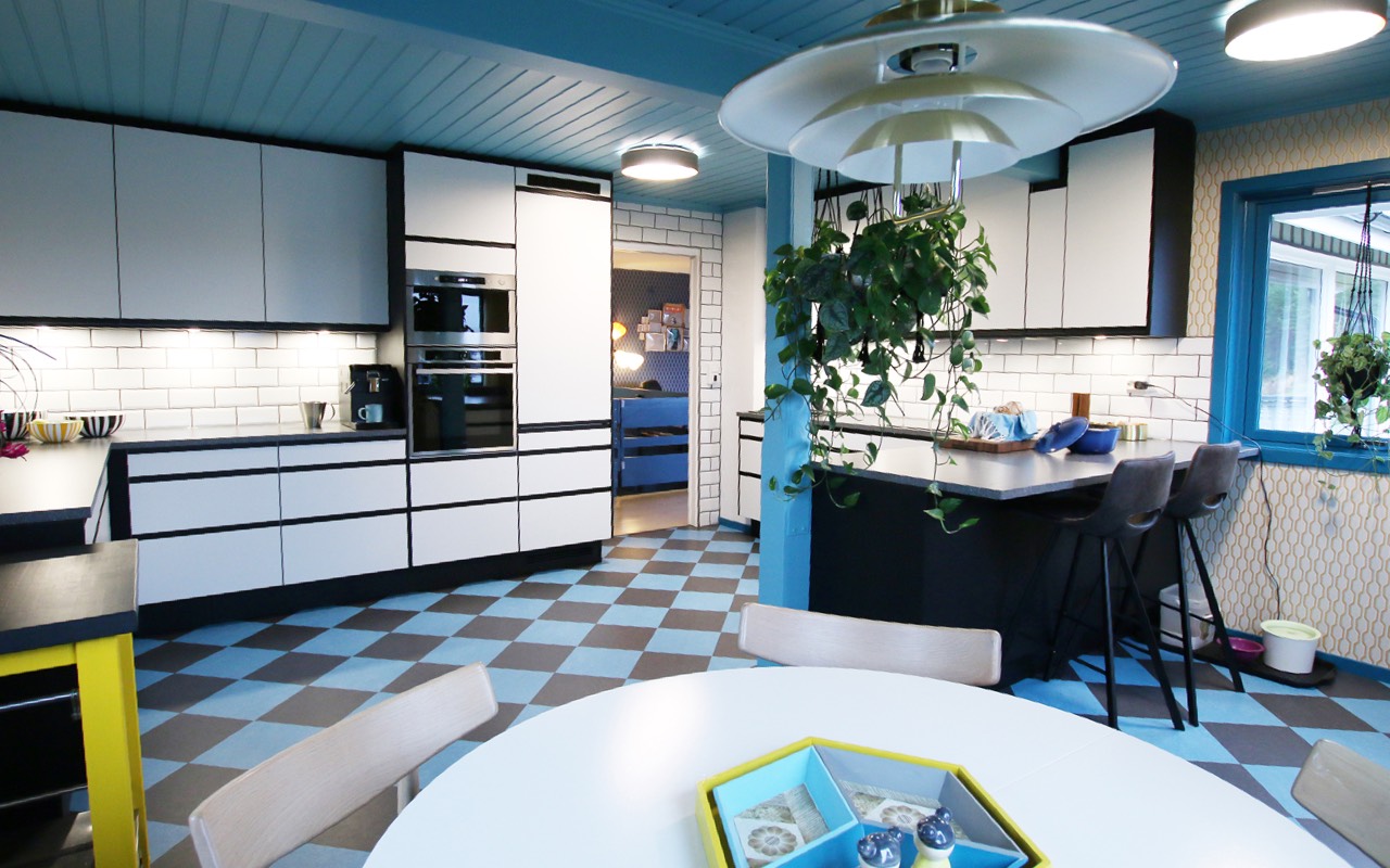 Fargebruk i kombinasjon med mønstret golv, fliser og tapeter skaper en intim og spennende ramme for kjøkkenet.